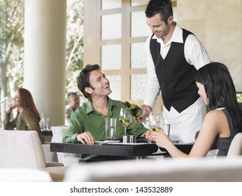 Waiter serving wine to young couple at outdoor restaurant - Powered by Shutterstock