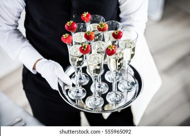 Waiter Standing With Champagne Glasses Next To Arranged Wedding Table