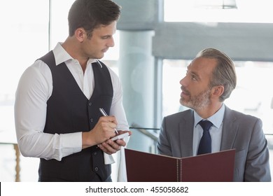 Waiter taking the order from a businessman in restaurant
