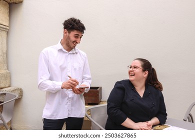 Waiter taking order from a cheerful woman in an outdoor restaurant environment - Powered by Shutterstock