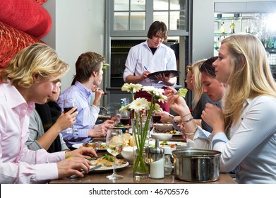 Waiter taking orders from a group of dinner guests at a restaurant