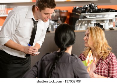 Waiter Taking Orders From Young Woman Customer In Restaurant