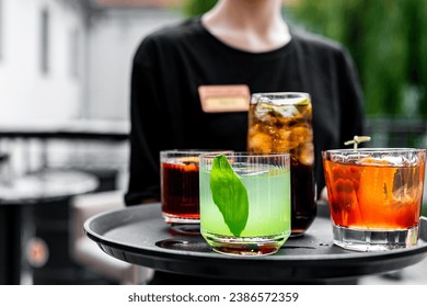 waiter with a tray of cocktails in a summer cafe - Powered by Shutterstock