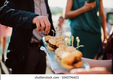 A waiter with a tray of snacks at a banquet or reception. Catering buffet at party