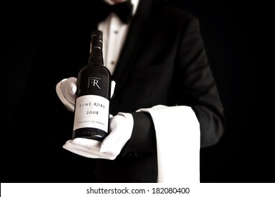 Waiter in tuxedo holding a bottle of red wine with custom designed label