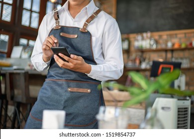 Waiter Using Touch Pad Or Smart Phone To Send Customer Order In The Restaurant. Modern Wireless Technology For Retaurant Or Coffee Shop.