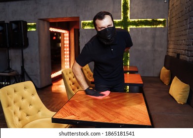 Waiter wearing protective face mask and gloves while disinfecting tables indoor restaurant, cafe. Precautions during the covid-19 coronavirus pandemic. - Powered by Shutterstock