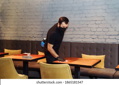 Waiter wearing protective face mask and gloves while disinfecting tables indoor restaurant, cafe. Precautions during the covid-19 coronavirus pandemic. - Powered by Shutterstock