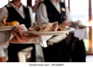 Waiters carrying plates with meat dish at a wedding