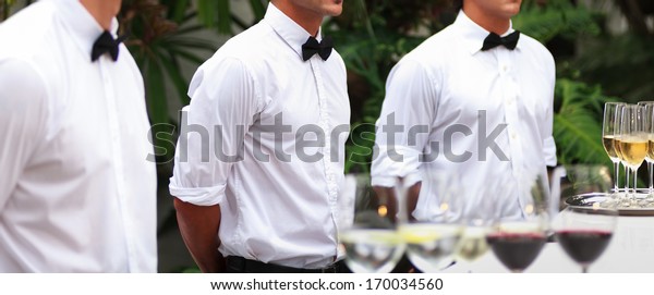 Waiters serving\
wine at a luxurious\
gathering.