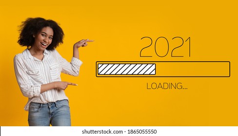 Waiting For 2021 New Year. Joyful Black Woman Pointing Finger At 2021 Loading Process Bar Standing Over Yellow Background. Anticipation, Awaiting Upcoming Better Year Concept. Panorama