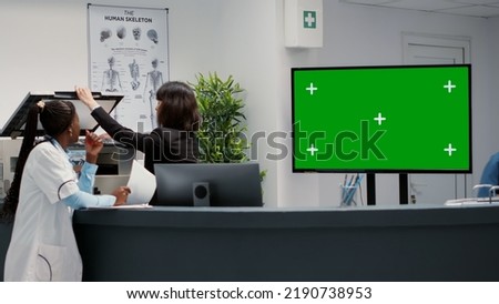 Waiting area and reception desk with greenscreen on tv display, hospital lobby in facility. Chroma key copyspace with isolated mockup background and blank template on monitor, healthcare.