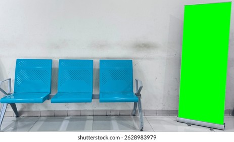 a waiting area with three empty, bright blue metal chairs with perforated backs and seats. To the right of the chairs stands a vibrant green, retractable banner stand.