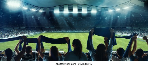 Waiting for beginning. Back view of football, soccer fans cheering their team with colorful scarfs at crowded stadium at evening time. Concept of sport, cup, world, team, event, competition - Shutterstock ID 2178580917