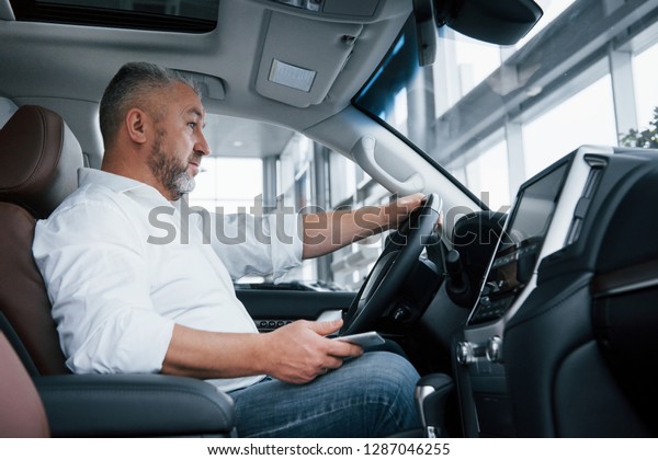 Waiting for a call. Businessman sits in the modern\
car and have some\
deals.
