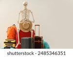 Waiting concept. Human skeleton with hat and suitcases near light wall, space for text