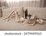 Waiting concept. Human skeleton with laptop on sofa indoors