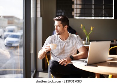 Waiting for inspiration. Shot of a young man working on a laptop in a cafe and drinking coffee. - Shutterstock ID 2139319083