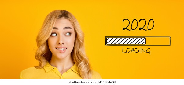 Waiting for new year. Blonde biting her lip and looking at 2020 loading process, yellow panorama background