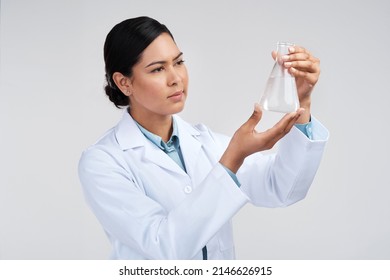 Waiting For The Reaction.... Cropped Shot Of An Attractive Young Female Scientist Examining A Beaker Filled With Liquid In Studio Against A Grey Background.