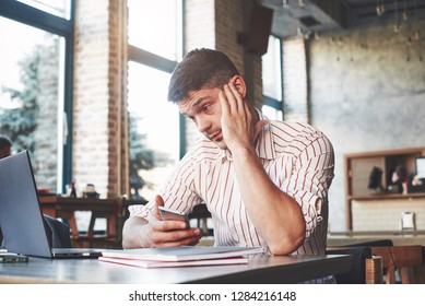 Waiting For The Response. Adult Man Sits In Cafe At Daytime And Using The Laptop For The Remote Work.