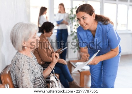 in waiting room of medical clinic, girl doctor interprets results of tests to surprised, annoyed female senior patient. Medical tourism