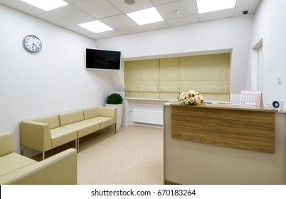 Waiting Room With TV In Modern Hospital Or Office, Light Interior And  Beautiful Decor. Reception, Counter, Sofa, Clock And Flowers In Clean Room, Design Of Entrance Hall.