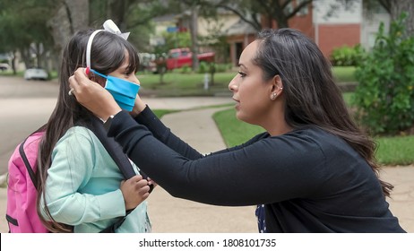 Waiting for the school bus to arrive this mom makes sure her daughter is wearing a mask on as mandated for all in person classroom attendance.