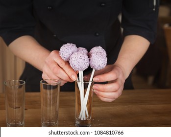 Waitress arranging candy bar. Putting cake pops with pink icing into glasses, closeup. Dessert table and catering concept for party, birthday, wedding and other holiday celebration - Powered by Shutterstock