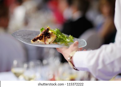 Waitress is carrying a plate with meat dish