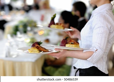 Waitress is carrying three plates with meat dish