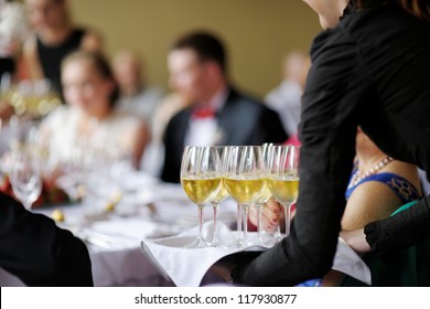 Waitress with dish of champagne and wine glasses