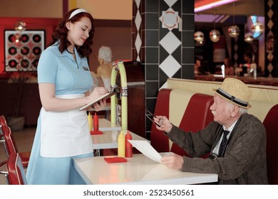 Waitress dressed in 1950s uniform taking order from elderly patron at retro diner table with vintage decor and neon lights reflecting classic diner ambiance - Powered by Shutterstock