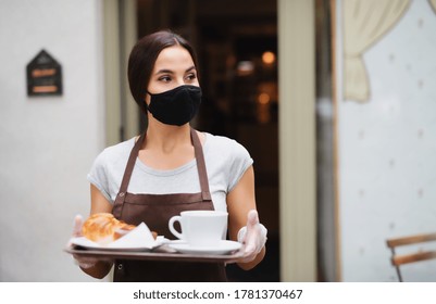 Waitress with face mask working in cafe, serving customers.