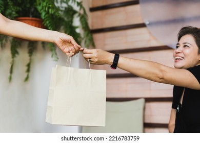 Waitress giving eco friendly paper bag to cheeful customer take out in cafe outdoor.