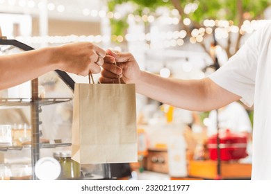 Waitress giving eco friendly paper bag to customer take out - Powered by Shutterstock