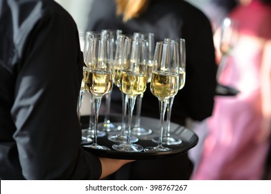 Waitress holding a dish of champagne and wine glasses at some festive event, party or wedding reception - Powered by Shutterstock