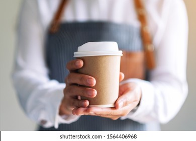 A Waitress Holding And Serving A Paper Cup Of Hot Coffee In Cafe