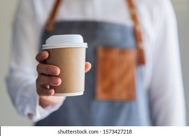 A waitress holding and serving a paper cup of hot coffee in cafe - Powered by Shutterstock