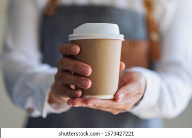 A waitress holding and serving a paper cup of hot coffee in cafe - Powered by Shutterstock
