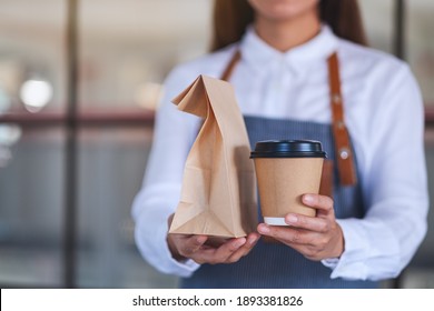 A Waitress Holding And Serving Paper Cup Of Coffee And Takeaway Food In Paper Bag To Customer In A Shop