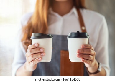 A Waitress Holding And Serving Two Paper Cups Of Hot Coffee In Cafe