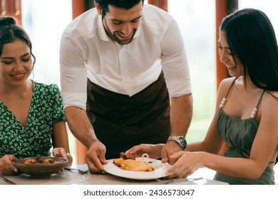 Waitress man serving food to group of diverse customer in restaurant, eatery client woman and man having smile and happy with service mind from cafes staff, lunch or dinner time lifestyle with family - Powered by Shutterstock