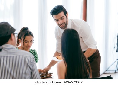 Waitress man serving food to group of diverse customer in restaurant, eatery client woman and man having smile and happy with service mind from cafes staff, lunch or dinner time lifestyle with family - Powered by Shutterstock