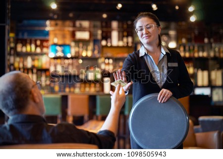 The waitress refuses to receive a tip from the client in the hotel bar. The girl is frustrated. Emotions. The concept of service.
