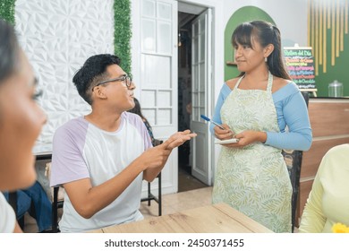 Waitress serving a man in the restaurant, seated. - Powered by Shutterstock