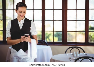 Waitress standing in restaurant using mobile phone