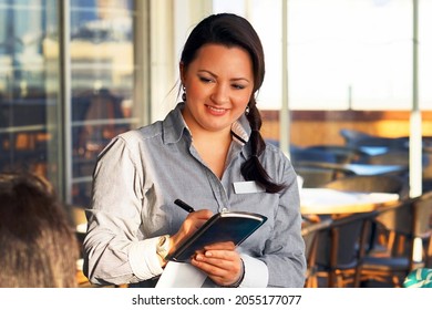 Waitress takes the customer's order in the hotel restaurant. Lunch time. The girl smiles cute. A girl waiter takes an order. Concept of service