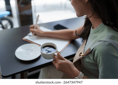 Waitress taking notes and drinking coffee while working in cafeteria
