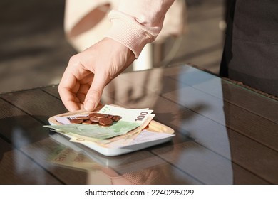 Waitress taking payment for order from wooden table at outdoor cafe, closeup. Leave tip